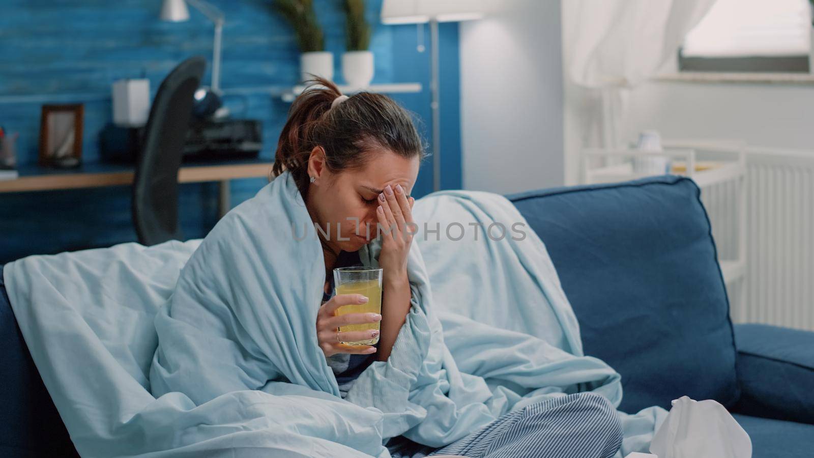 Sick woman with headache drinking effervescent vitamin drink to cure cold and flu. Adult with glass of medication as disease treatment having virus symptoms. Person with illness