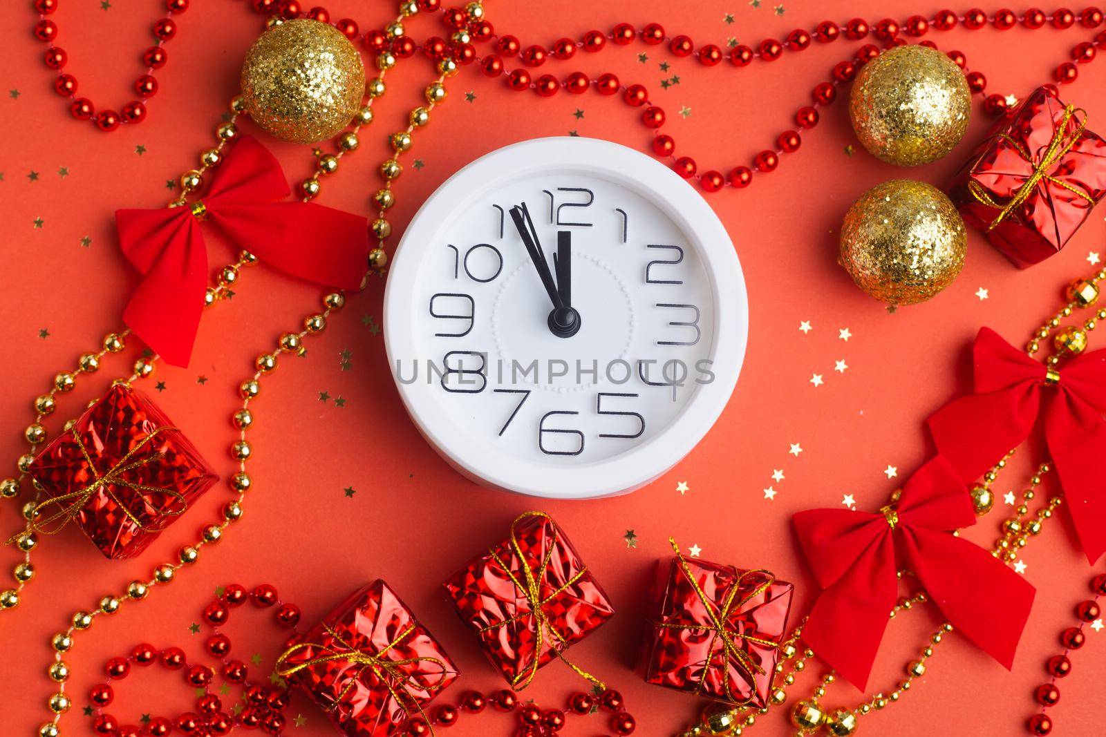 A clock in a New Year's layout on a red background. New Year's gifts. An article about the New Year and Christmas. It's almost 12 o'clock