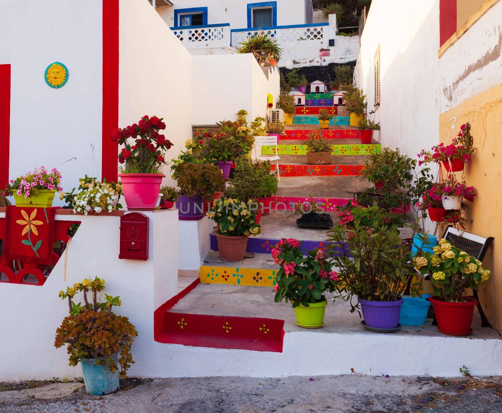 View of a typical colored house in Linosa with the staircase full of flower pots