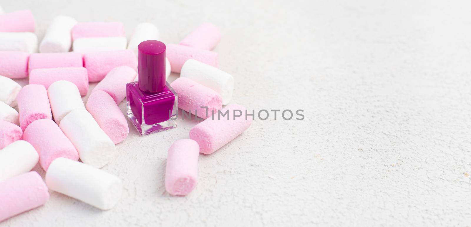 Nail polish and marshmallows . Marshmallow on a white background. An article about nail polishes. Cosmetology. Decorative cosmetics. Copy Space