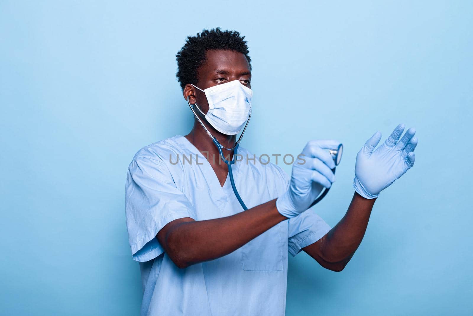 Medical nurse holding stethoscope to listen to heartbeat for cardiology examination. Cardiologist with instrument wearing face mask and gloves against coronavirus pandemic for healthcare