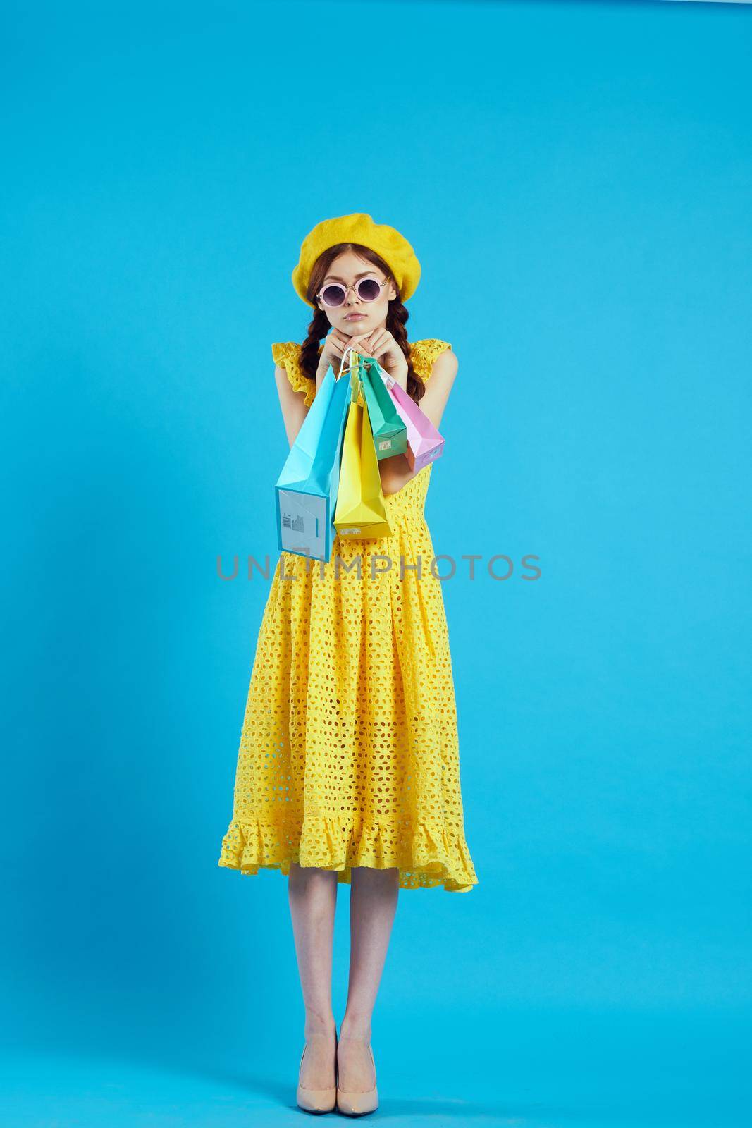 cheerful woman yellow dress shopping fun blue background by Vichizh