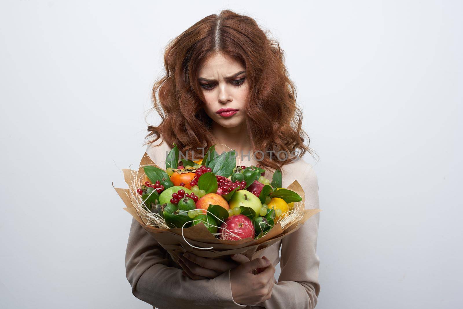 cheerful woman bright makeup attractive look a bouquet of fruits light background. High quality photo