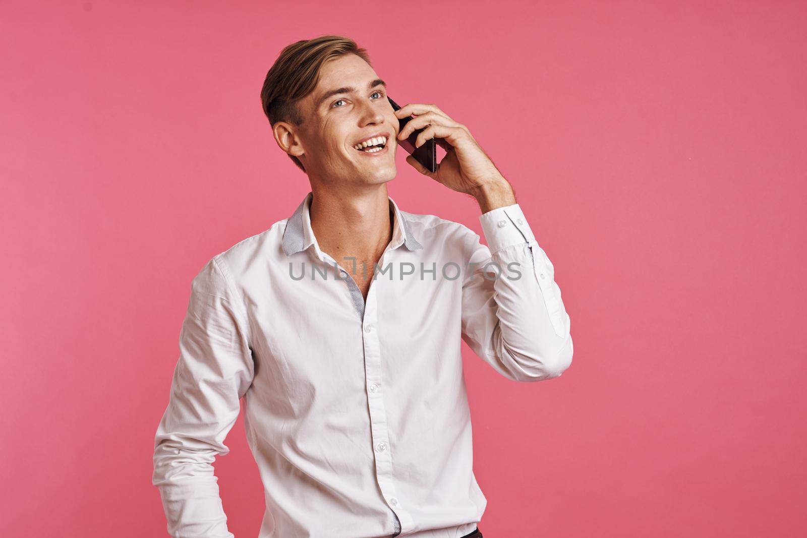 businessmen in a white shirt talking on the phone pink background. High quality photo