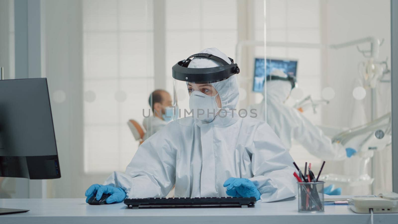 Stomatology assistant sitting at desk using computer by DCStudio