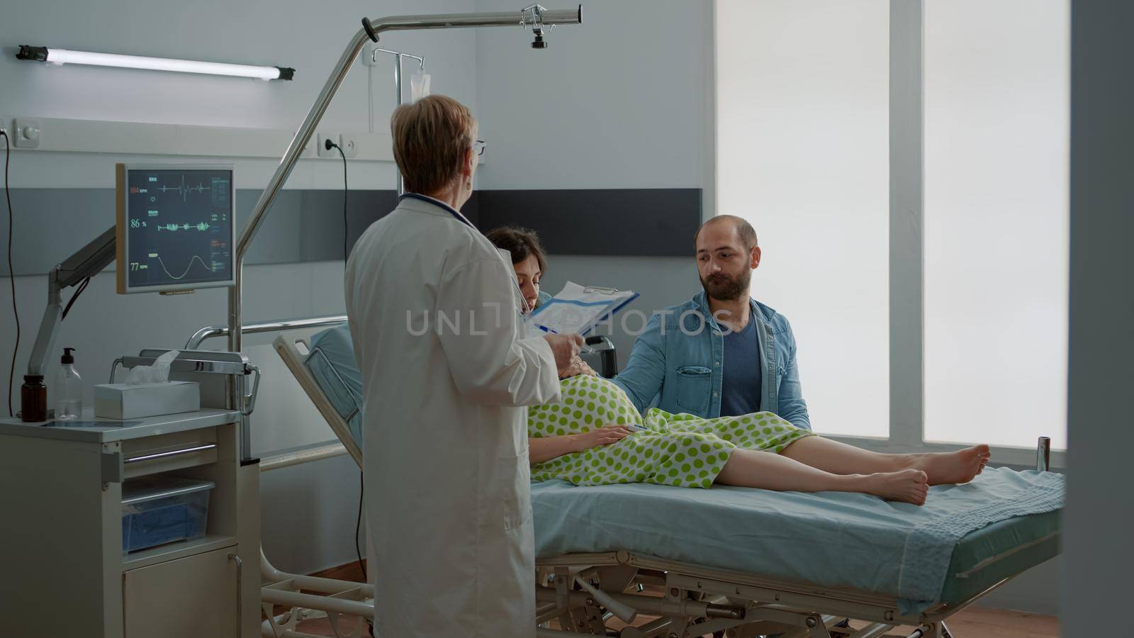 Maternity doctor giving advice to pregnant woman and husband sitting in hospital ward. Young caucasian couple getting medical parenthood assistance from childbirth specialist at clinic