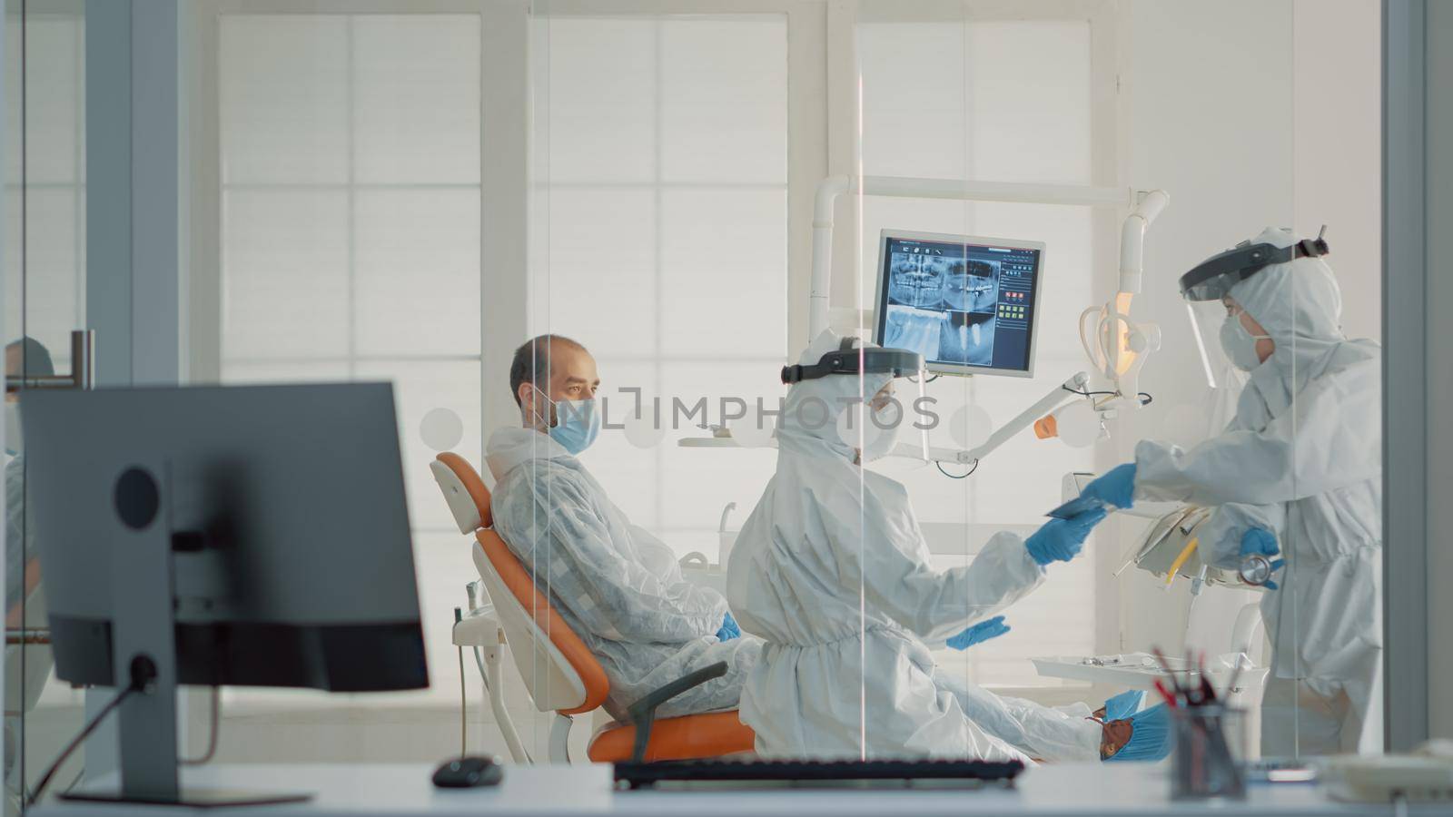 Stomatology nurse giving dental x ray to dentist in cabinet for patient teeth consultation at oral clinic. Caucasian professional orthodontic staff using modern dentistry equipment