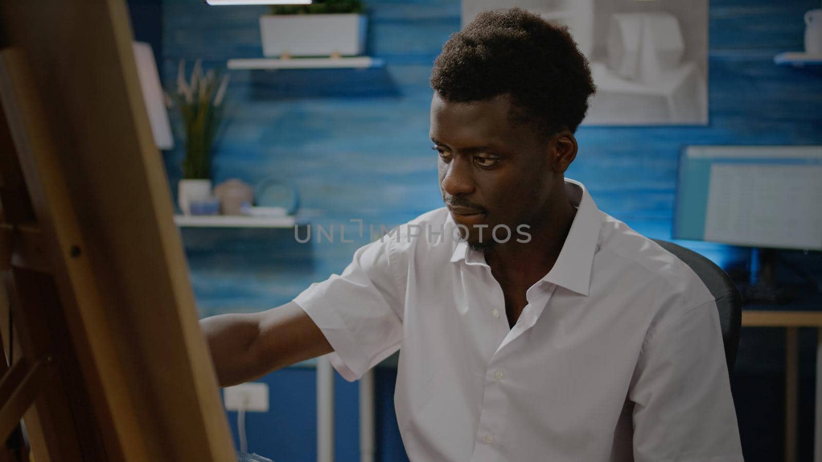 Black artist using pencil and white canvas on easel for design and drawing process in workshop space. African american person creating beautiful masterpiece for fine art concept