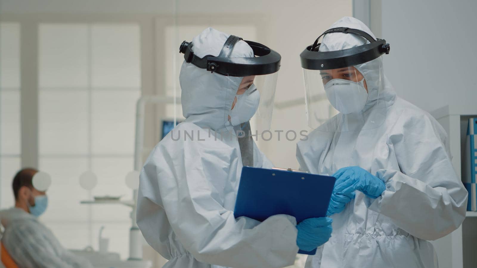 Close up of dentistry doctors talking wearing hazmat suit with face shield, mask, and coverall. Caucasian dentist team discussing dental operation and consultation for teeth protection