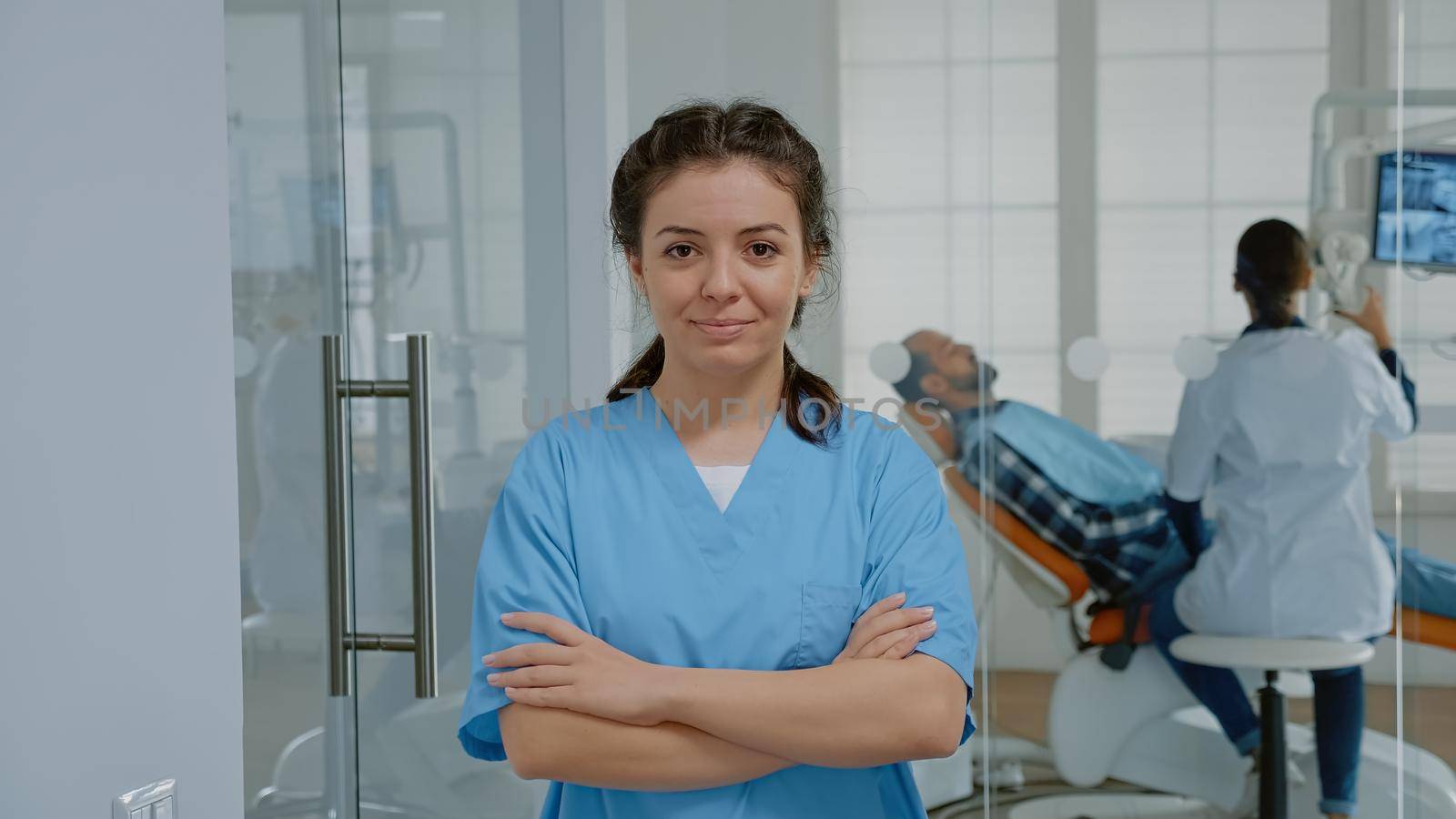 Portrait of assistant woman looking at camera in stomatology office. Caucasian adult with nurse profession and medical expertise standing at teethcare clinic wearing uniform