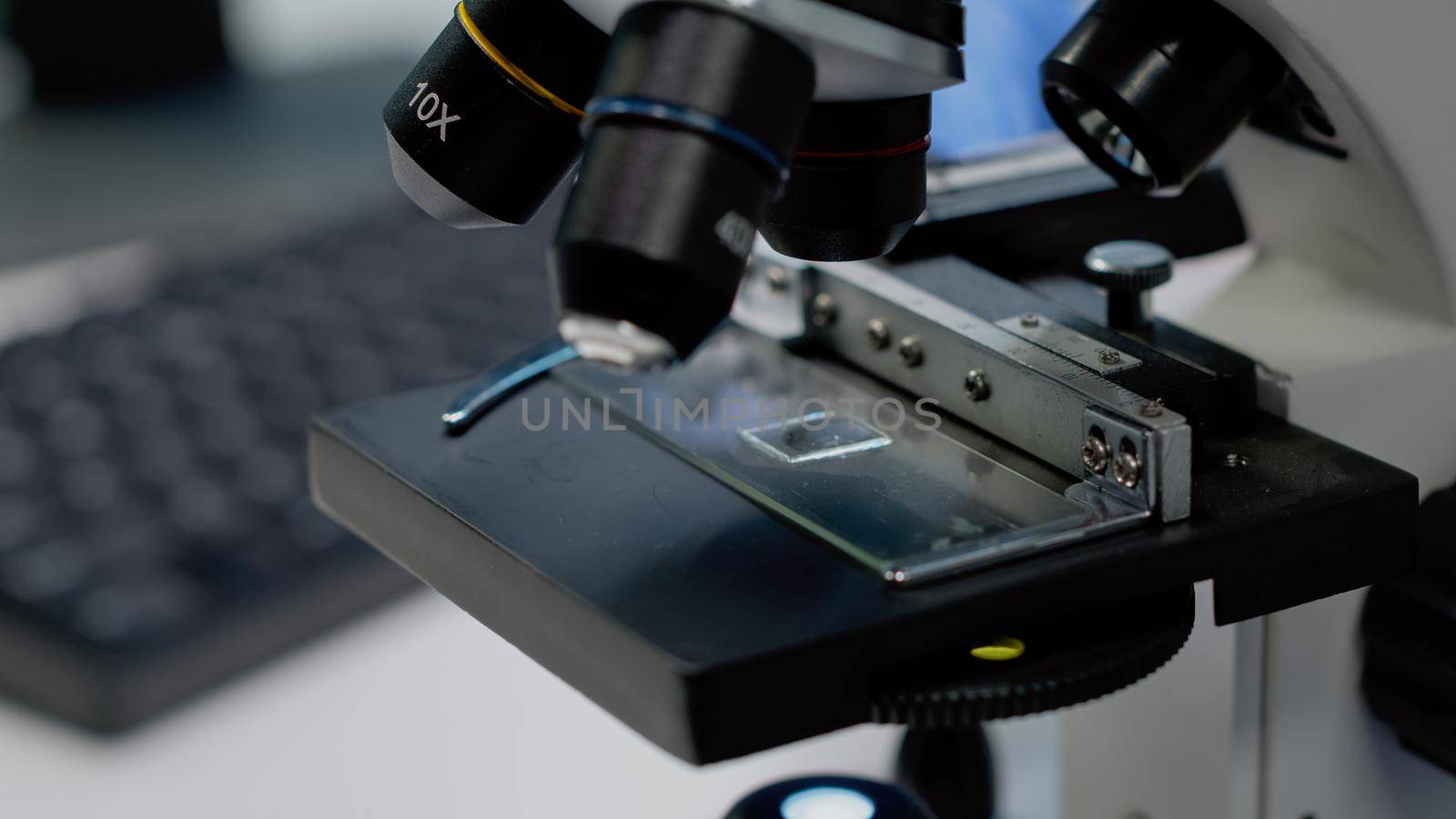 Close up of microscopic sample tray for optical analysis in laboratory. Microscope with magnifying lens used for dna and bacteria investigation in pharmaceutical research industry