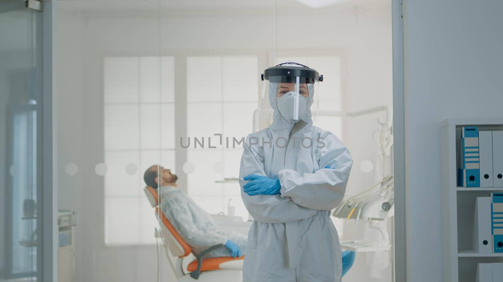 Portrait of dentist standing in hazmat suit for virus protection at oral clinic. Caucasian woman wearing coverall ppe prepared for dentistry operation and surgical consultation