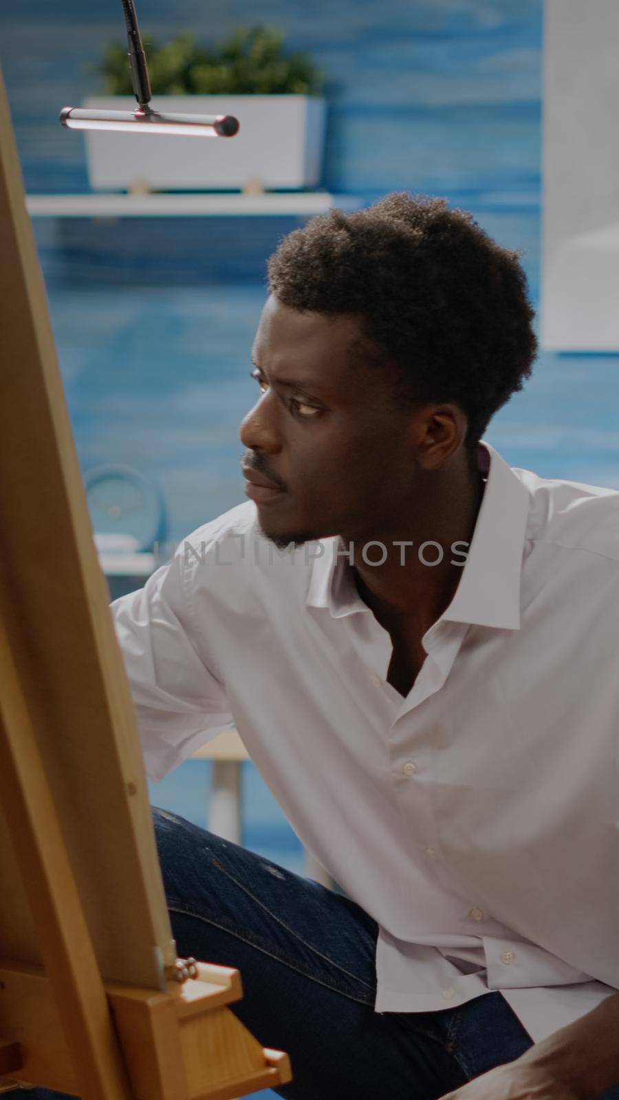Artist of african american ethnicity working on drawing of vase at art studio. Black young adult using pencil and canvas on easel for creative masterpiece. Person with fine art project