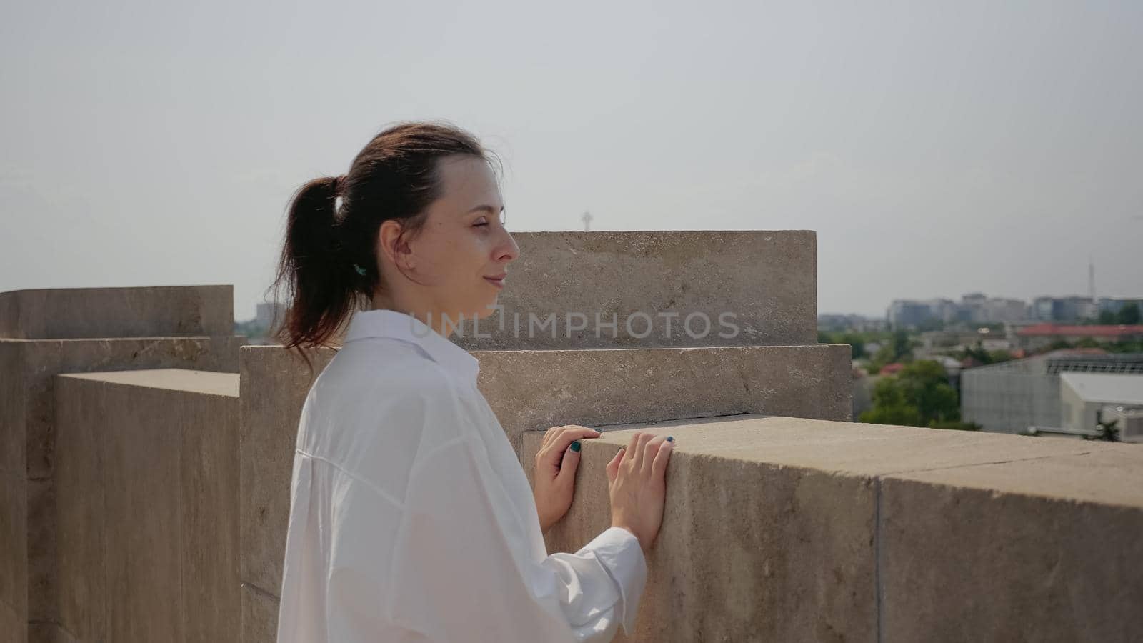 Young woman watching cityscape from observation point by DCStudio