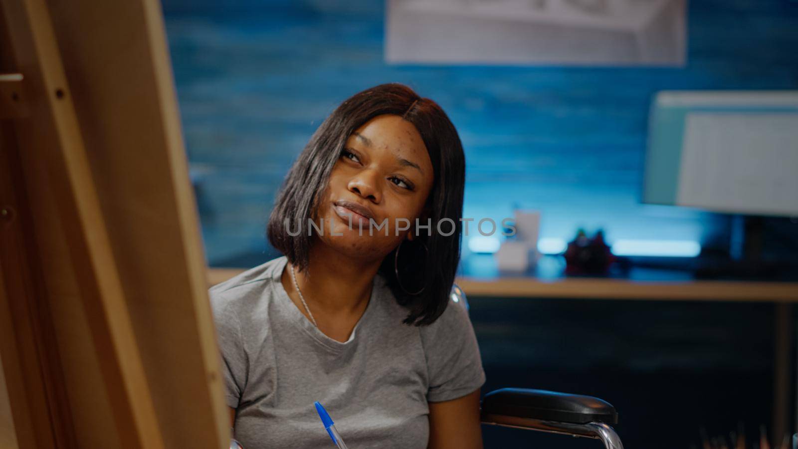 Portrait of african american woman with disability drawing sketch for fine art project. Black paralyzed artist sitting in wheelchair preparing for modern masterpiece. Artistic hobby