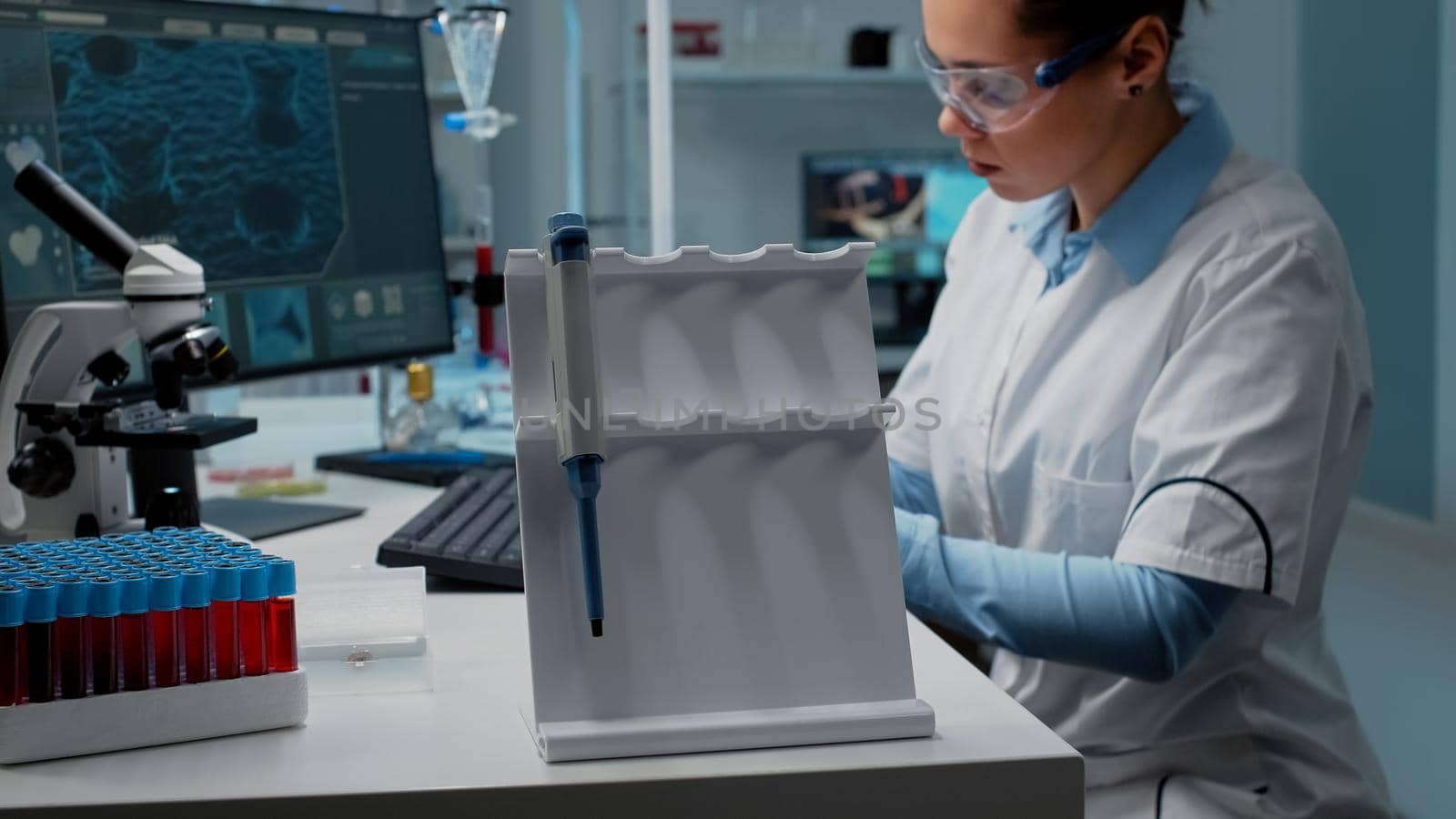 Close up of scientist using micropipette at laboratory desk for chemical research in medical industry. Biochemistry doctor with computer, vacutainer and scientific equipment wearing lab coat