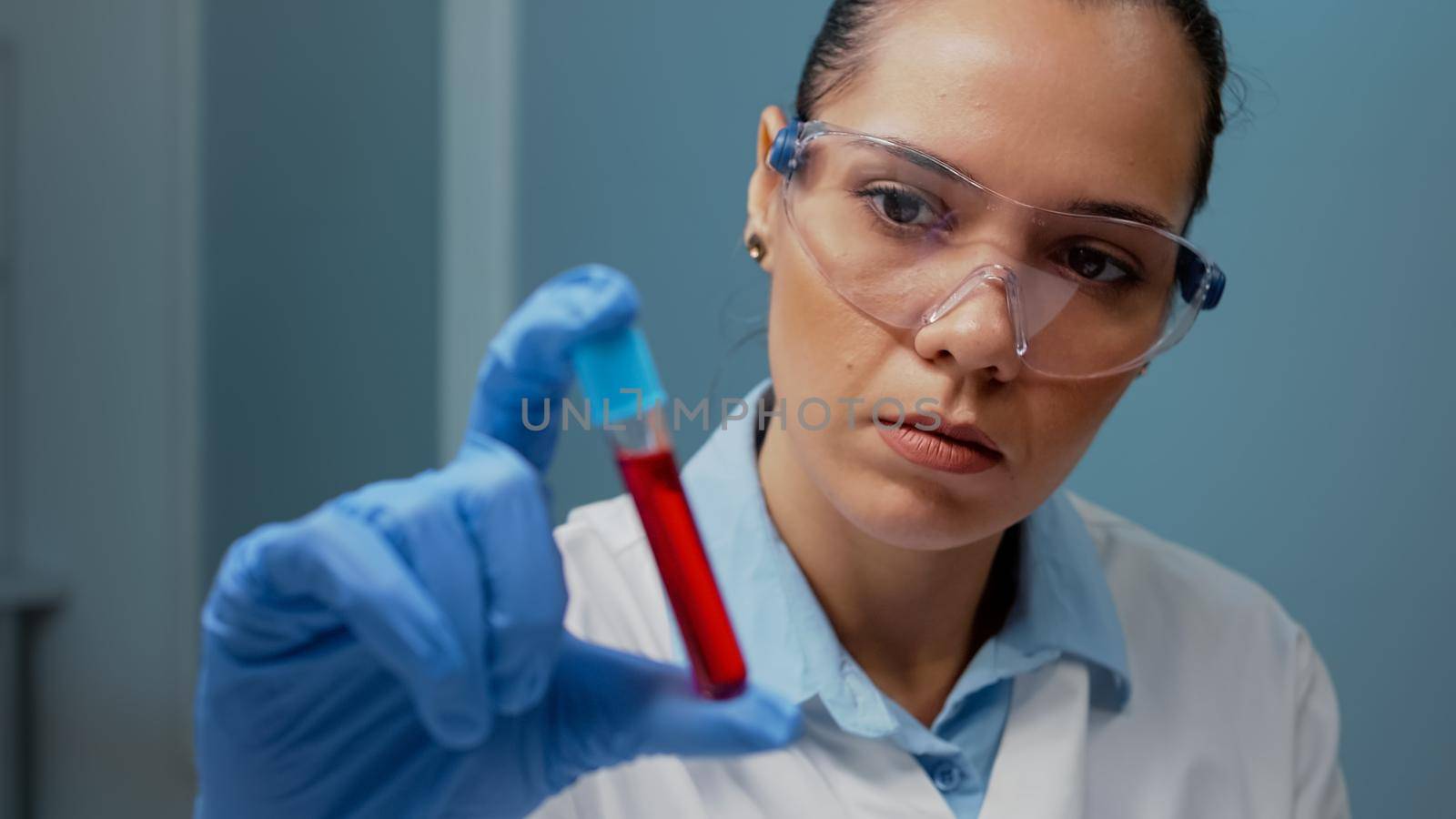 Laboratory scientist holding vacutainer with blood sample by DCStudio