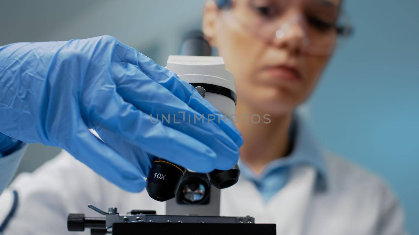 Close up of doctor using optical lens on microscope in biochemistry laboratory. Specialist using microscopic magnifying glass instrument for dna investigation and genetic bacteria