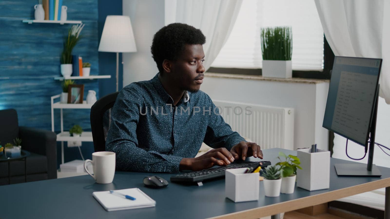 Black man computer user working from home in cozy flat by DCStudio