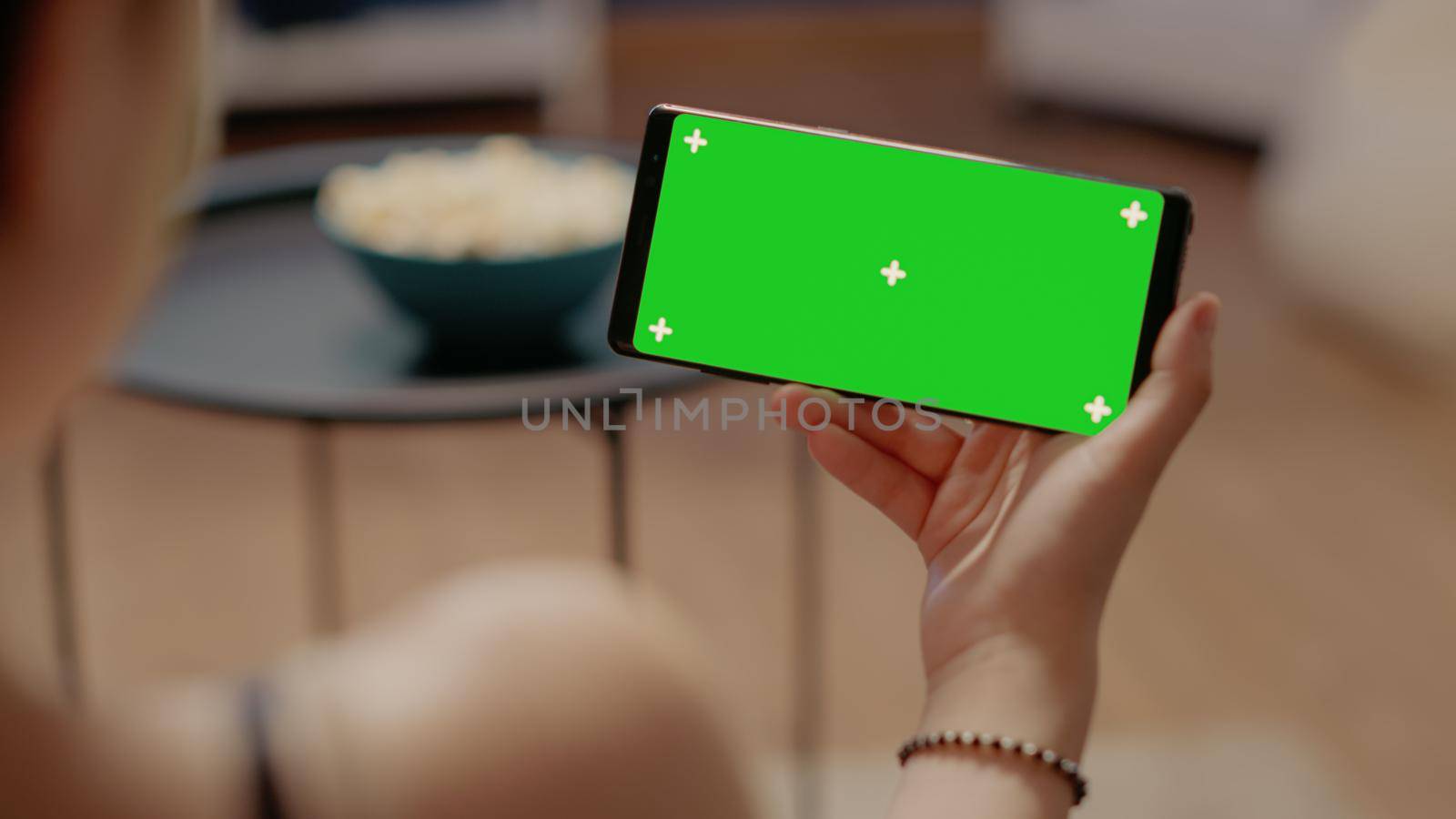 Close up of horizontal smartphone with green screen used for chroma key with isolated media background and mockup template. Caucasian young woman holding copy space modern device