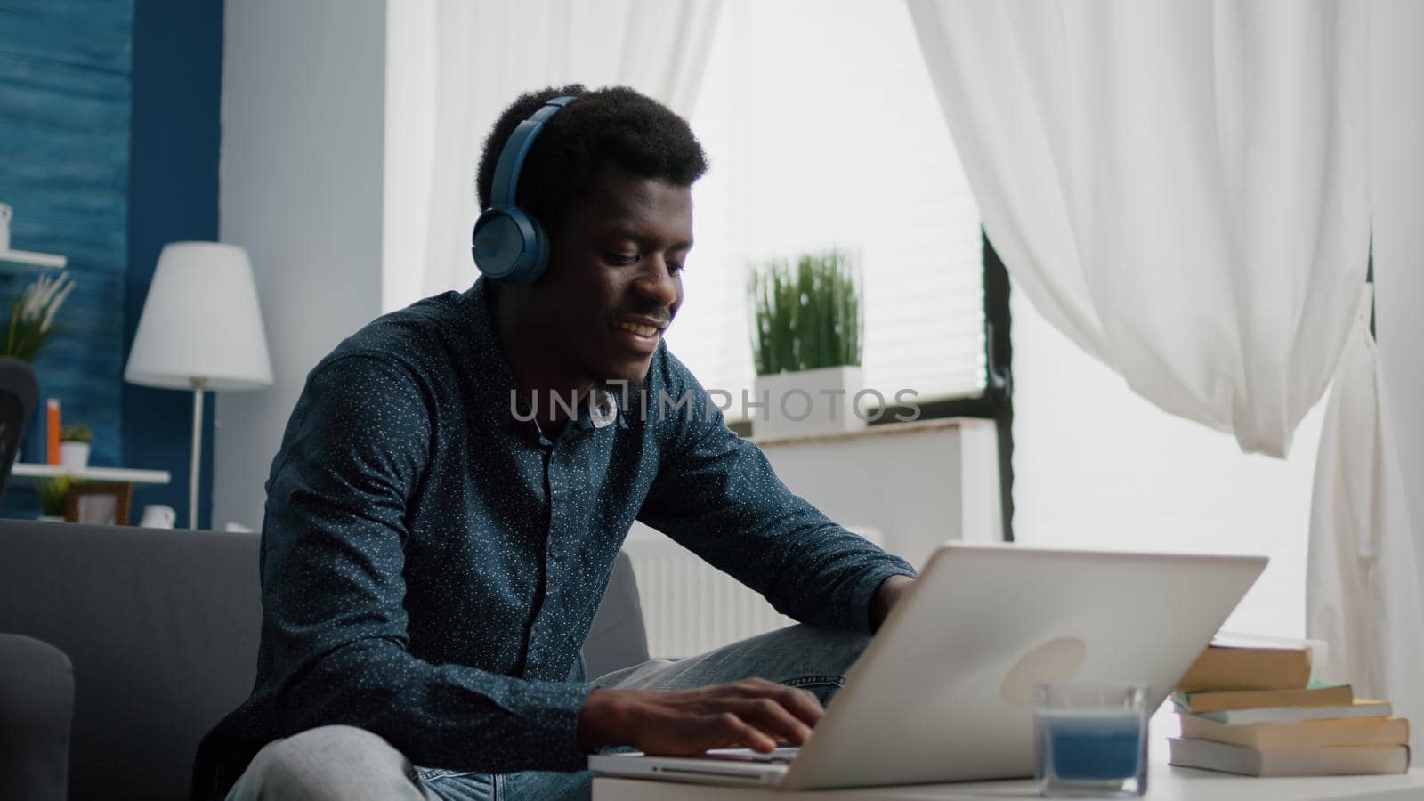 Black african american man wearing headphone, typing on laptop by DCStudio