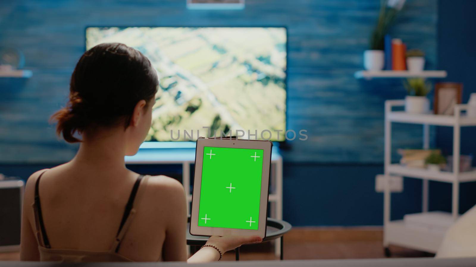 Caucasian woman holding green screen vertically on digital tablet looking at chroma key template and isolated mockup virtual background. Young person with modern equipment of copy space