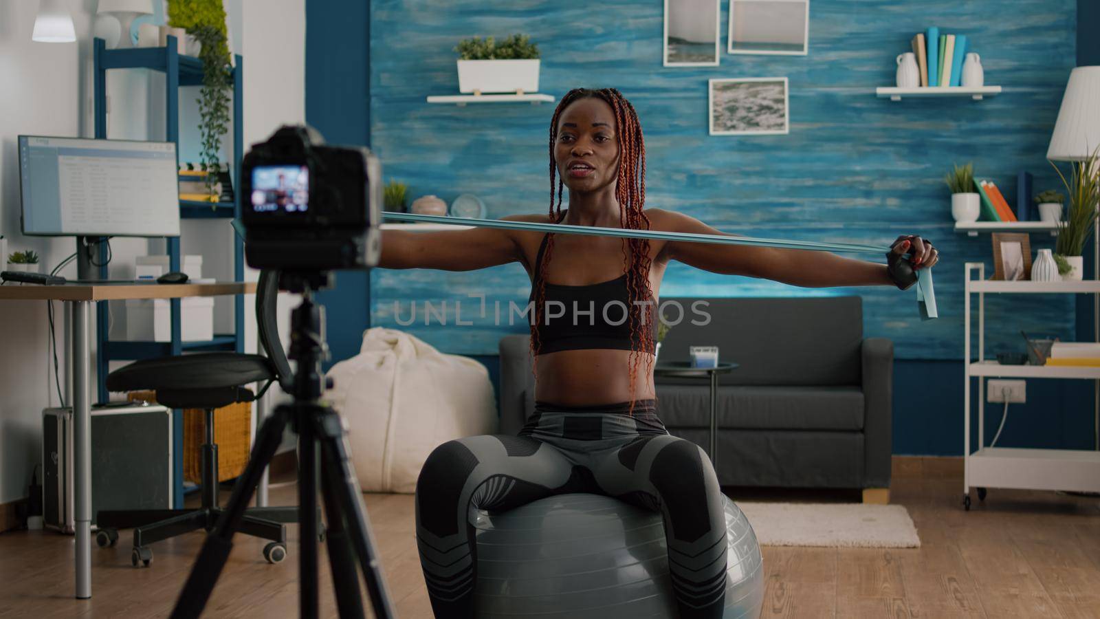 Athletic slim woman with black skin recording online yoga class using videocamera by DCStudio