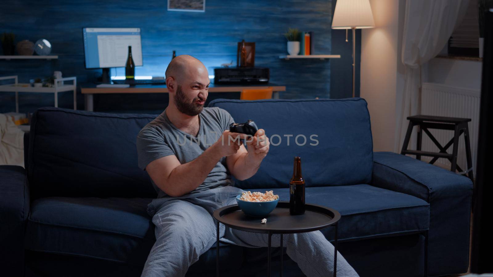 Determinated excited man sitting on sofa playing video games, happiness scream enjoying online competition. Competitive gamer using controller joysticks playstation gaming and having fun winning