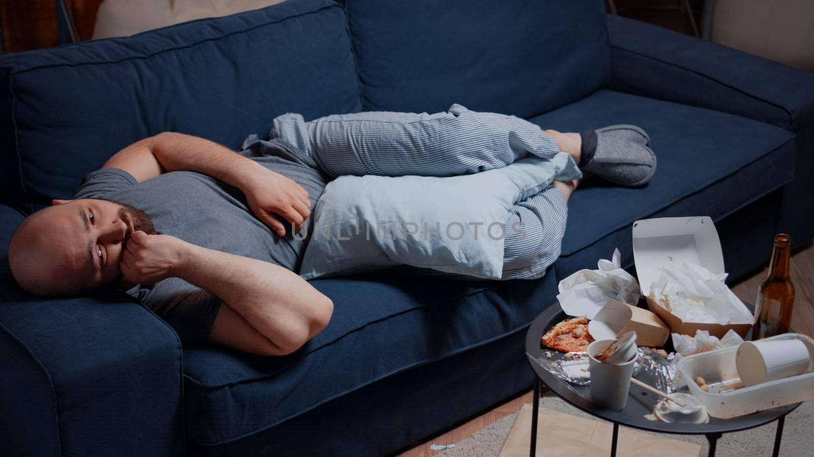 Adult man unable to enjoy life because of major depression, bipolar disorder, mental problem, anxiety, crying and feeling unhappy, vulnerable, traumatized. Depressed, sad, desperate male lying on sofa