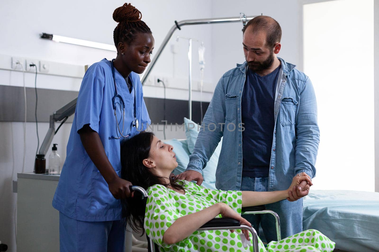 Pregnant woman in wheelchair getting assistance from nurse by DCStudio