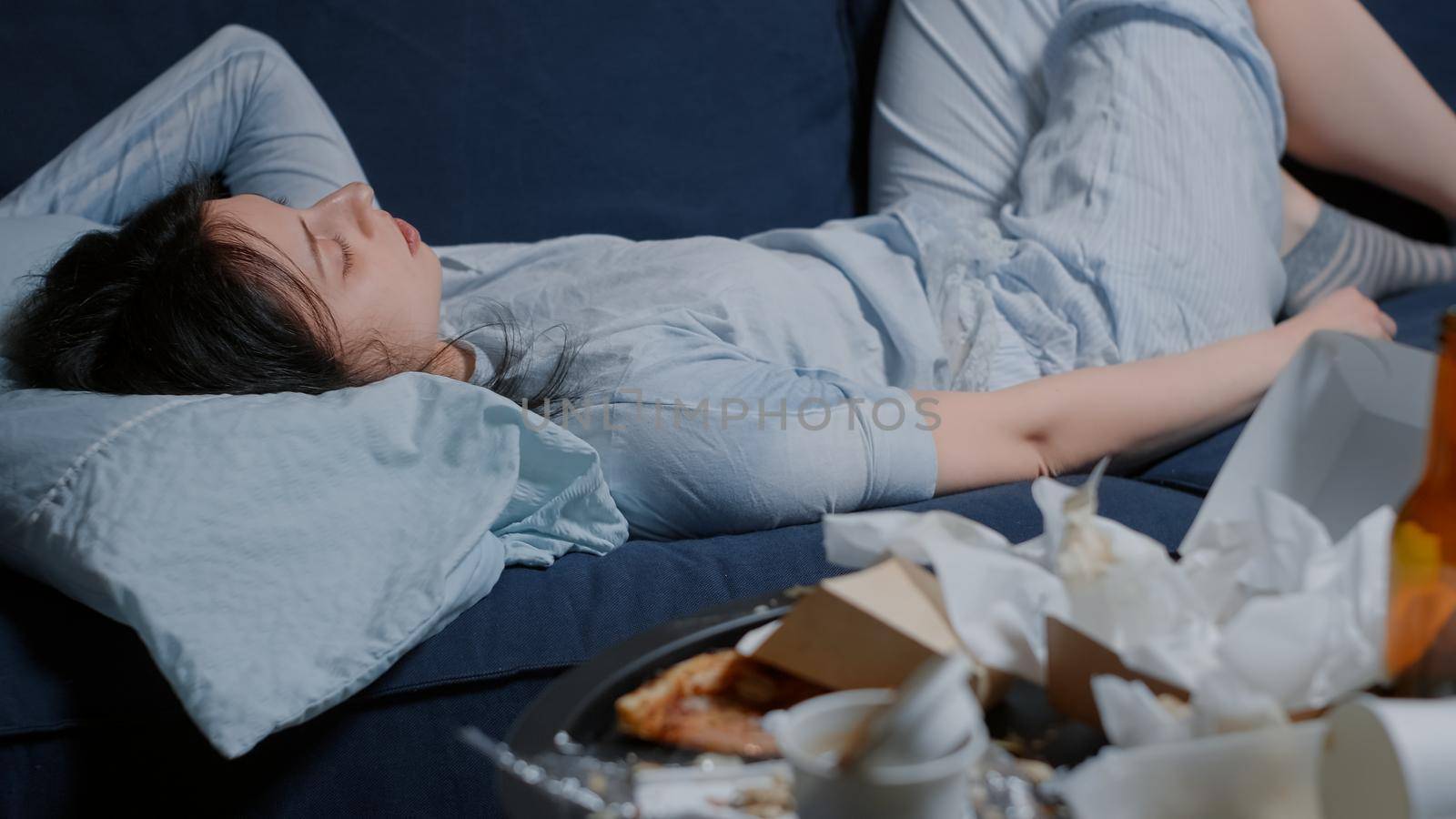Unhappy depressed woman lying on sofa looking lost at messy table holding napkin. Person in depression crying feeling hopeless disappointed frustration suffering from break up mental problems
