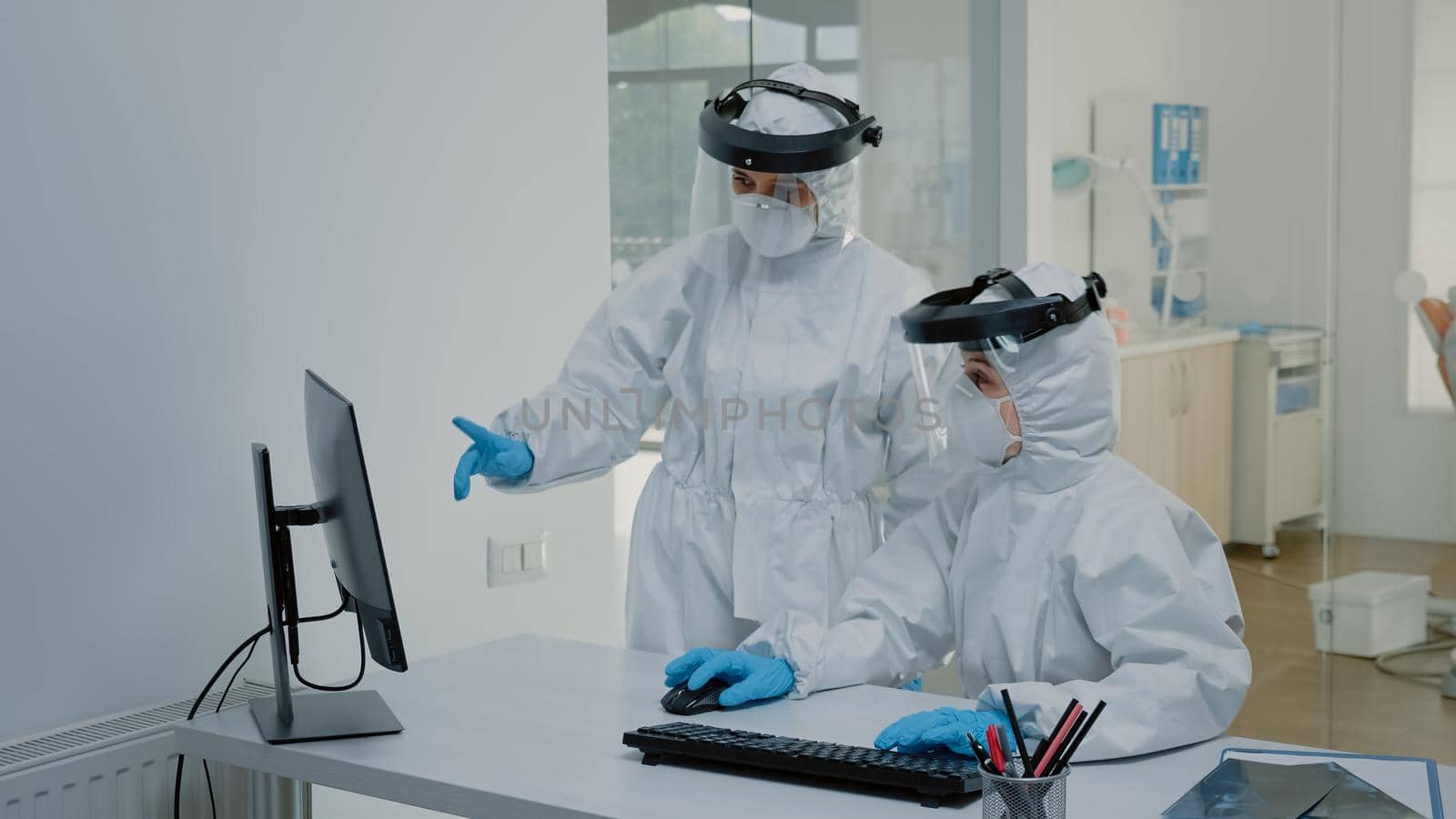 Dentistry staff wearing ppe suits discussing dental x ray scan by DCStudio
