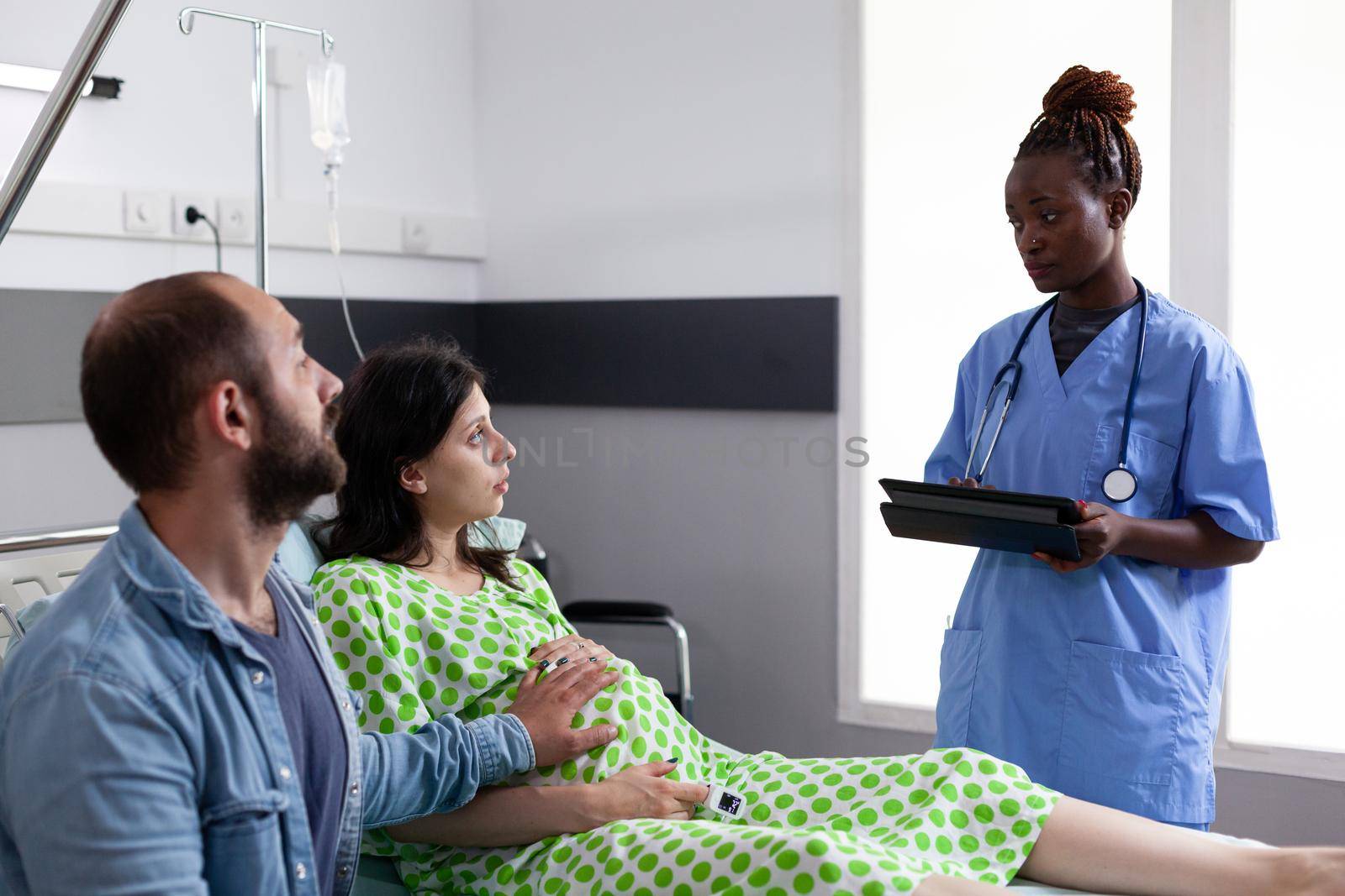 African american nurse monitoring healthcare of pregnant woman by DCStudio