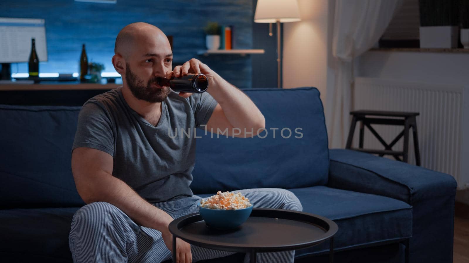Upset pro gamer sitting in front of television losing soccer video games holding wireless controller, joystick. Frustrated man for gaming over drressing in pajama relaxing playing online competition