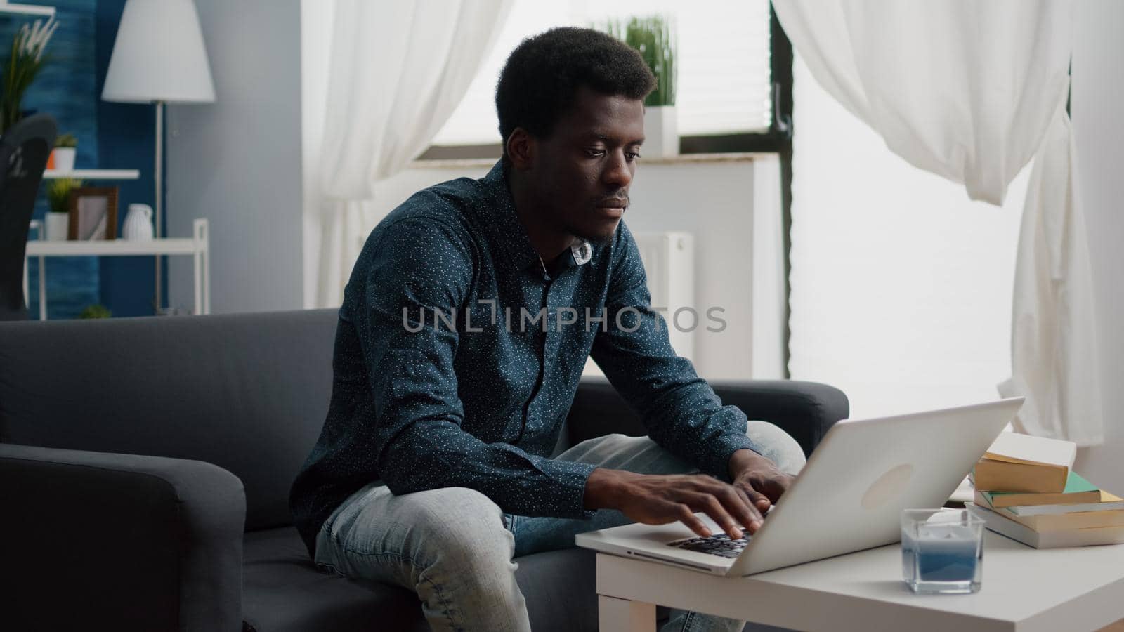 Working from home black man in flat apartment, happy african american remote worker using laptop computer, male workplace for online internet business, using social media