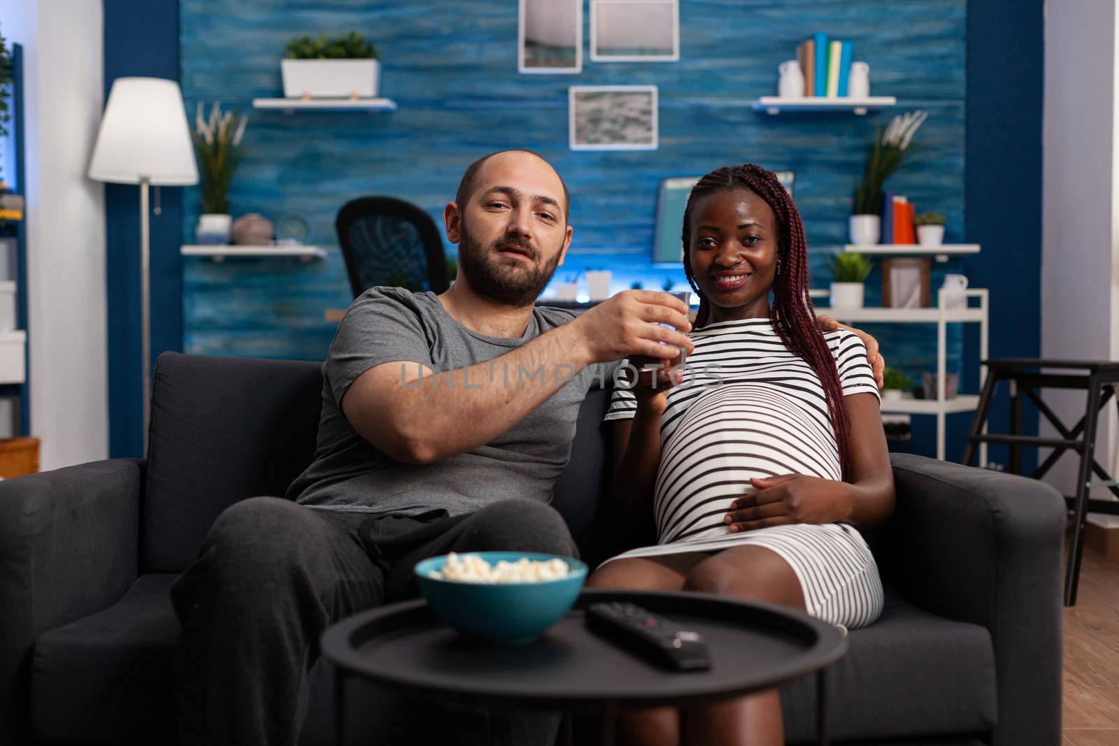 POV of interracial couple with pregnancy watching movie by DCStudio
