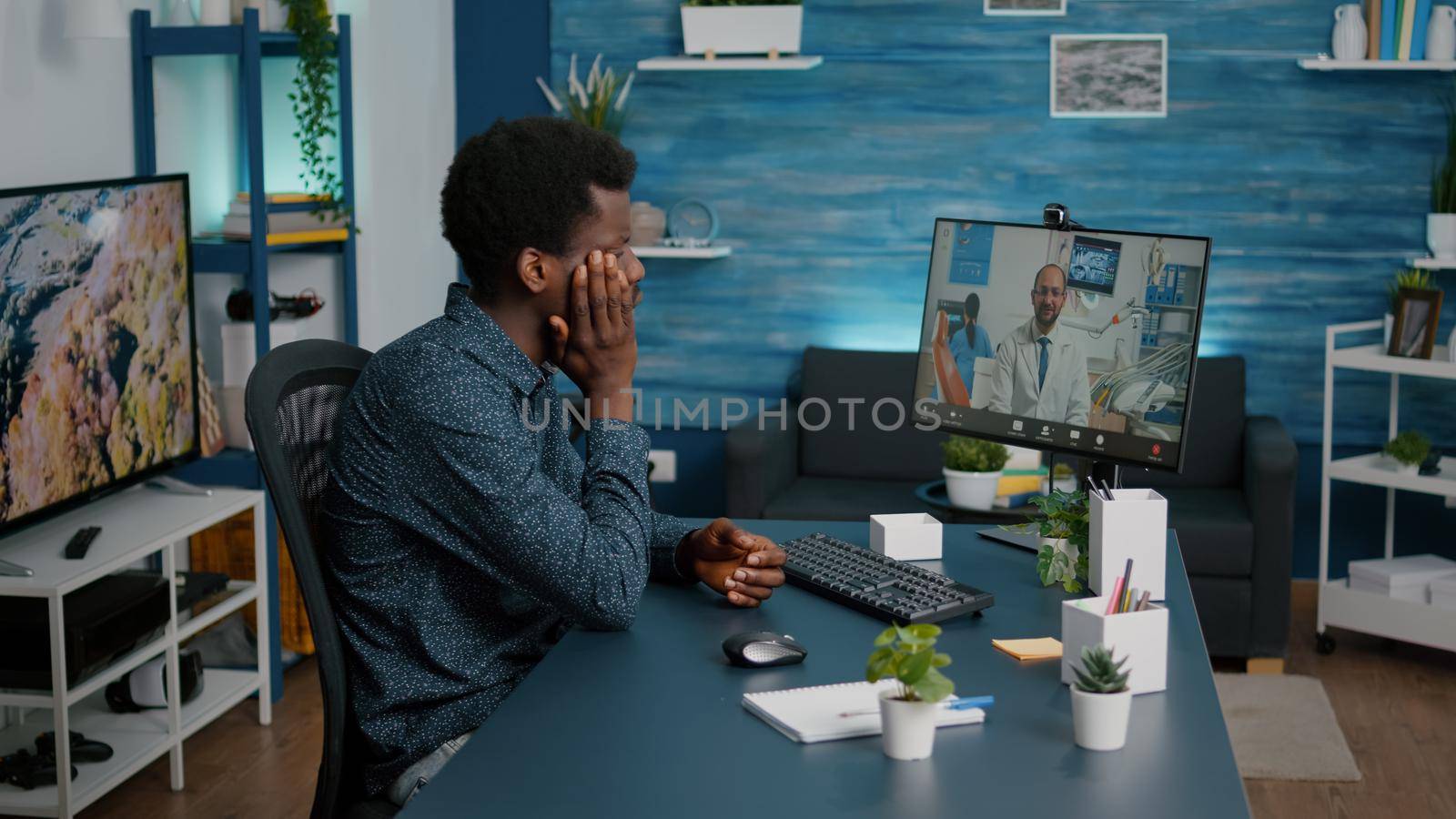 Black man with toothache seeking medical stomatologist health advice via internet video call communication. Online telehealth diagnose using webcam teethcare consultation, dental hygiene and orthodontist advice