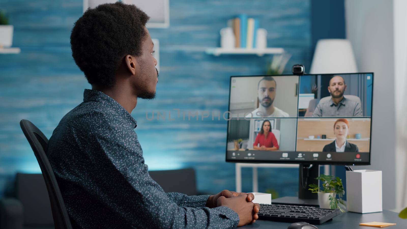 Selective focus on african american man on online conference video call with his colleagues. Computer user working from home in home office chatting using internet distance communication
