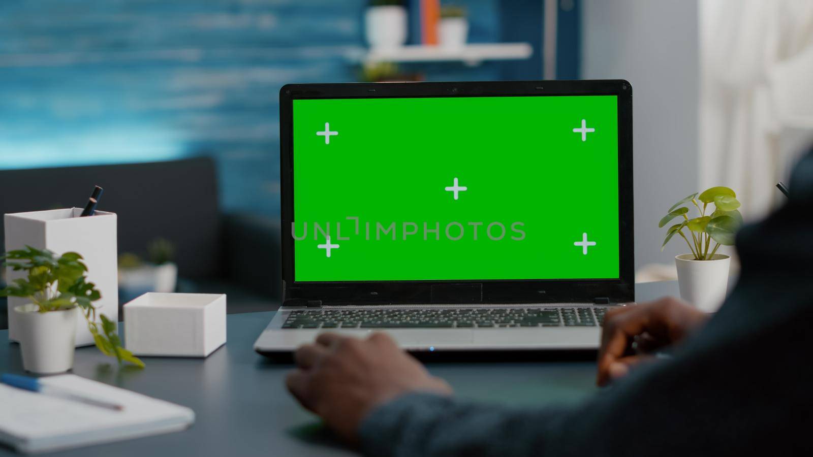 Close up of african american man using green screen laptop in bright living room. Computer usir with isolated chroma key mockup mock up display