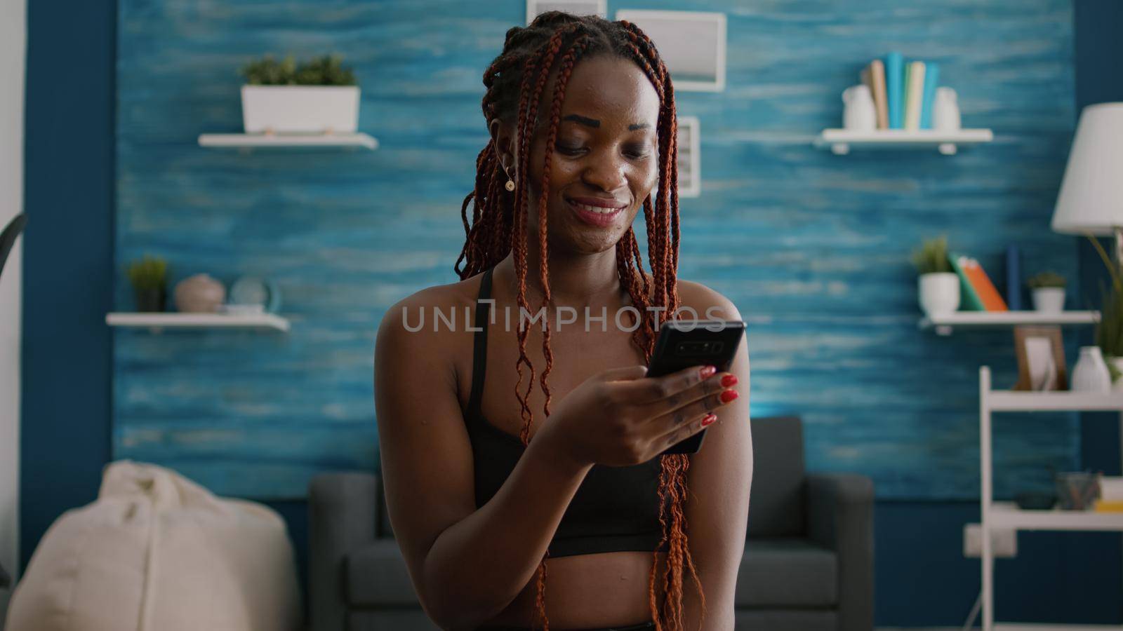 Fit atheltic woman with black skin wearing sportswear sitting on yoga swiss ball by DCStudio