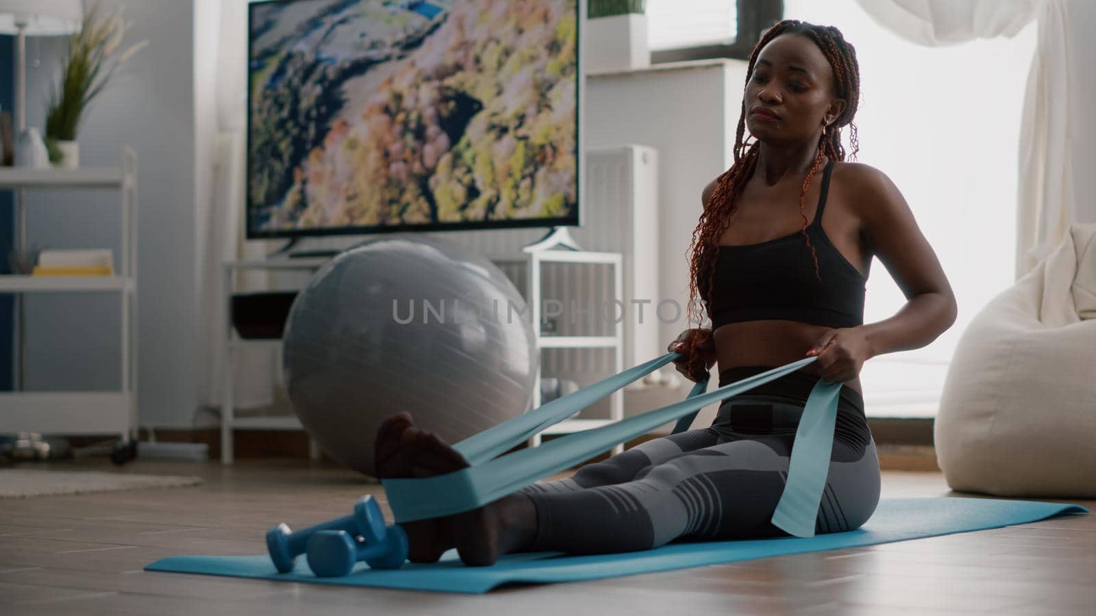 Athlete with black skin in sportswear exercising body muscle using fitness elastic by DCStudio