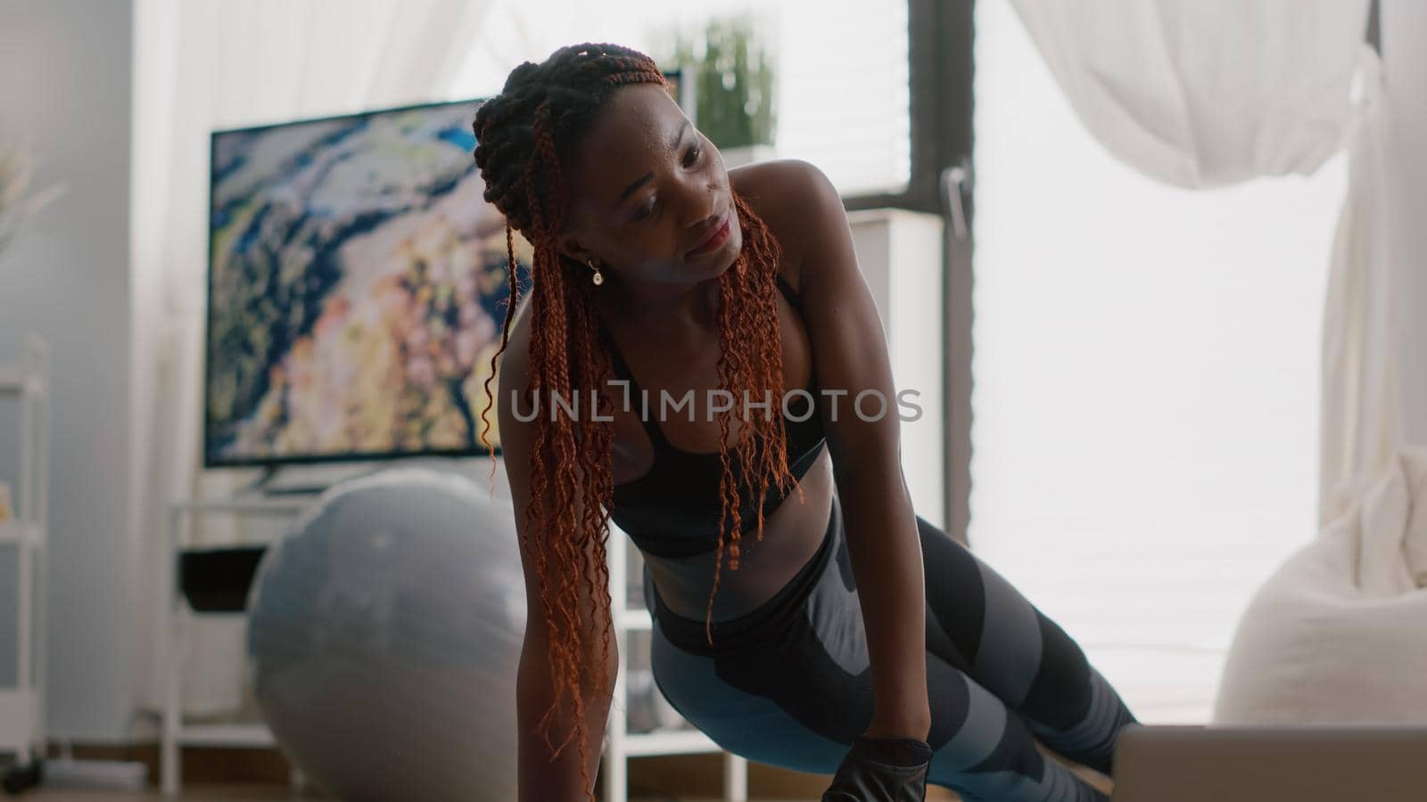 Afro american fit woman wearing sportswear doing leg exercises by DCStudio