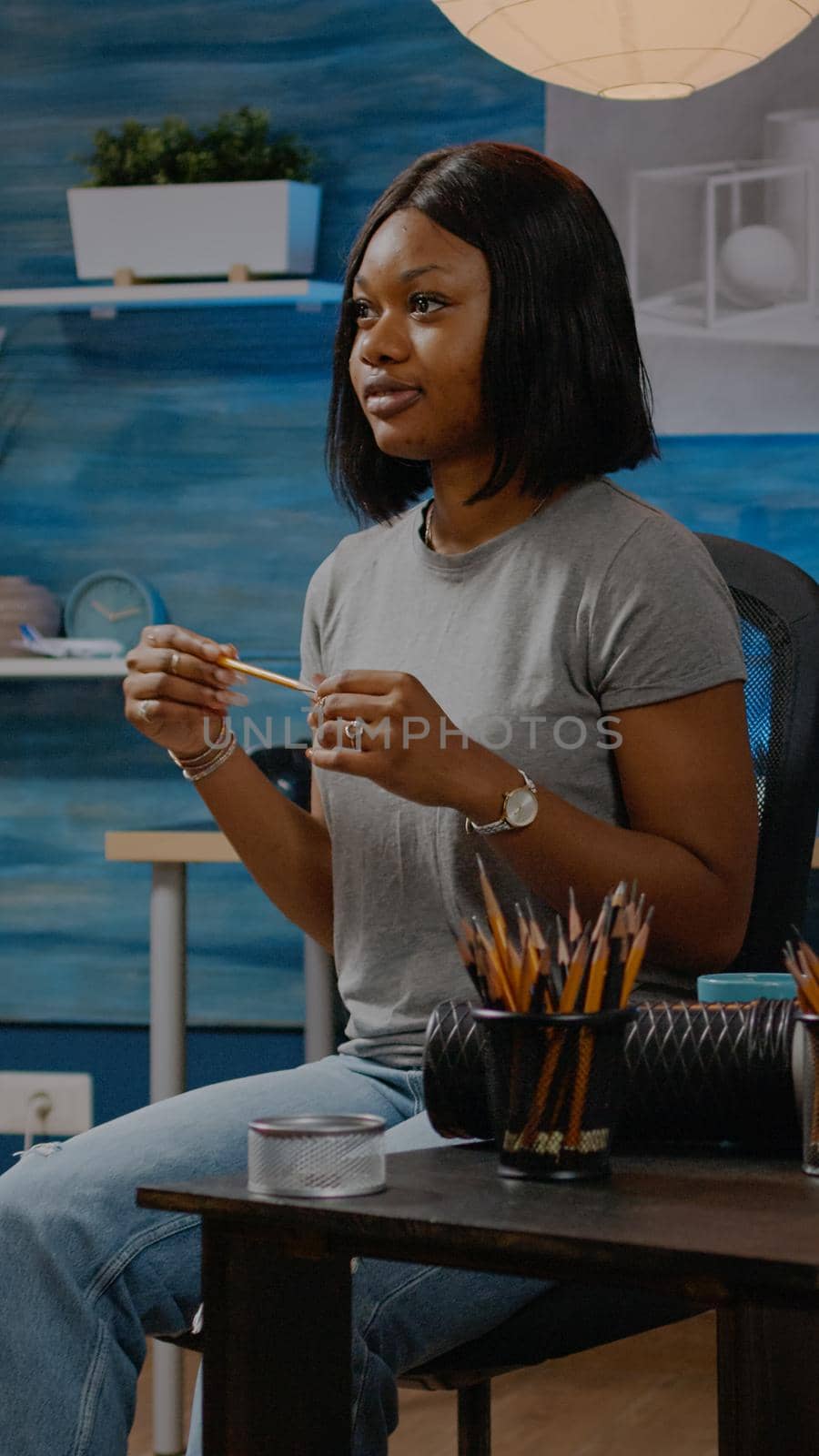 Black young artist working on vase drawing at home in artwork studio. African american woman using art tools, pencil and white canvas on easel creating authentic masterpiece as hobby