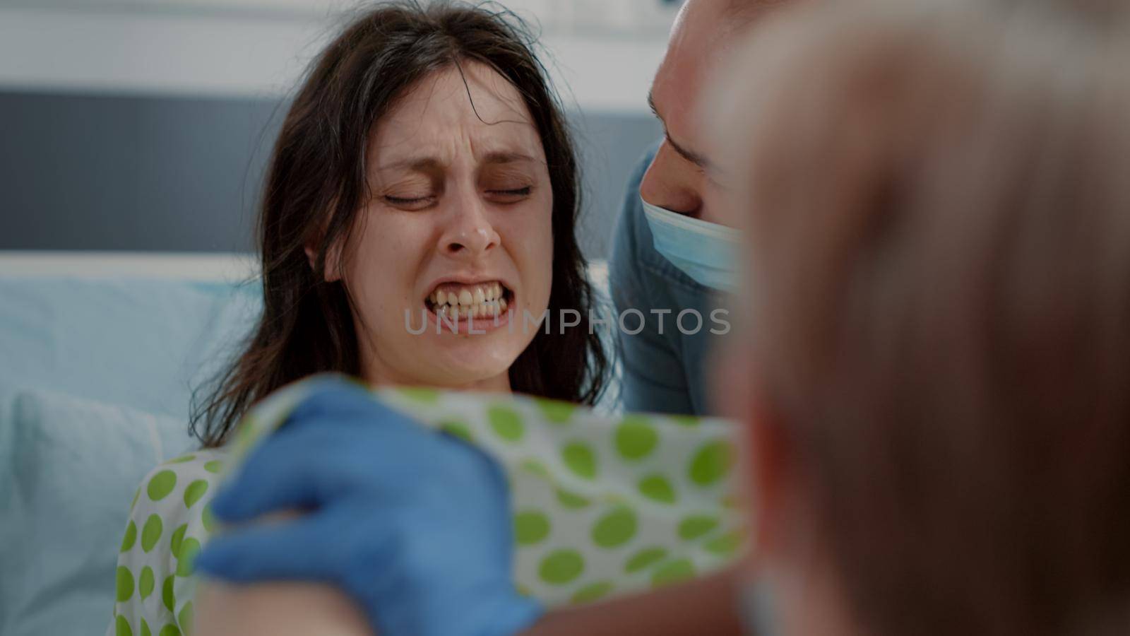 Close up of pregnant woman pushing and screaming in hospital ward at clinic. Young person giving birth while being in pain. Caucasian husband supporting wife with contractions and childbirth