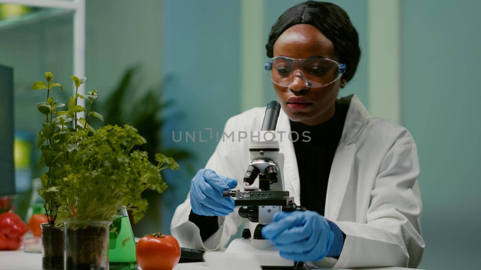 Portrait of pharmaceutical woman putting slide under microscope by DCStudio