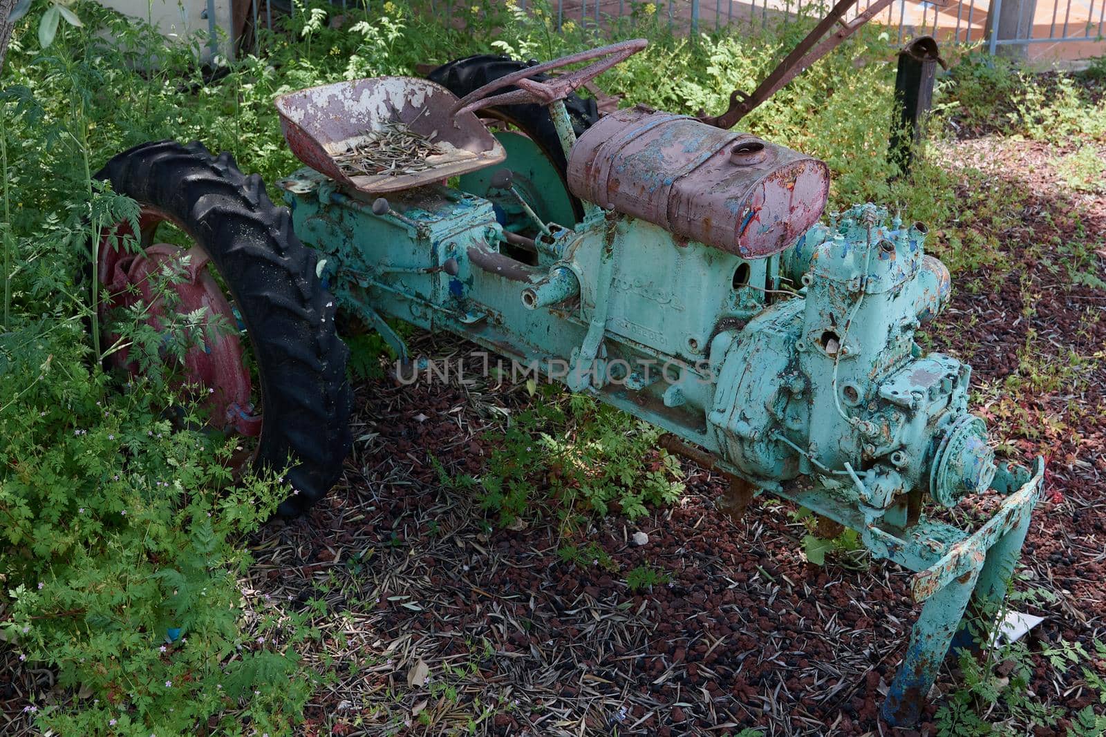 an old tractor skeleton with peeling paint in different colors many layers of pink and light green shades