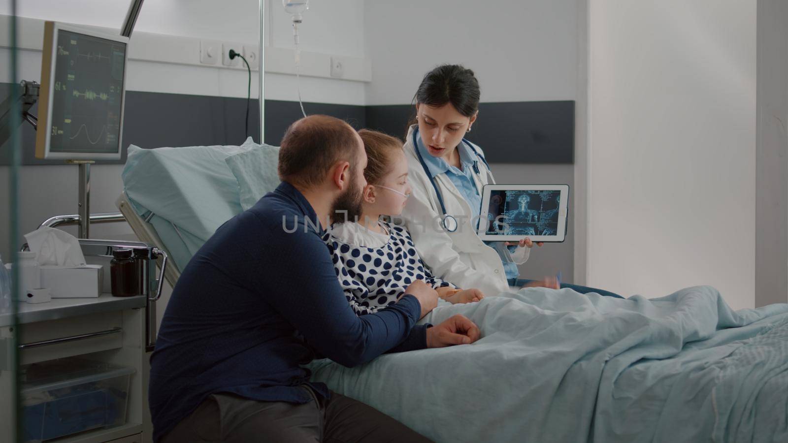 Physician woman doctor explaining medical radiography discussing healthcare treatment monitoring symptoms during recovery examination in hospital ward. Hospitalized child having breathing illness