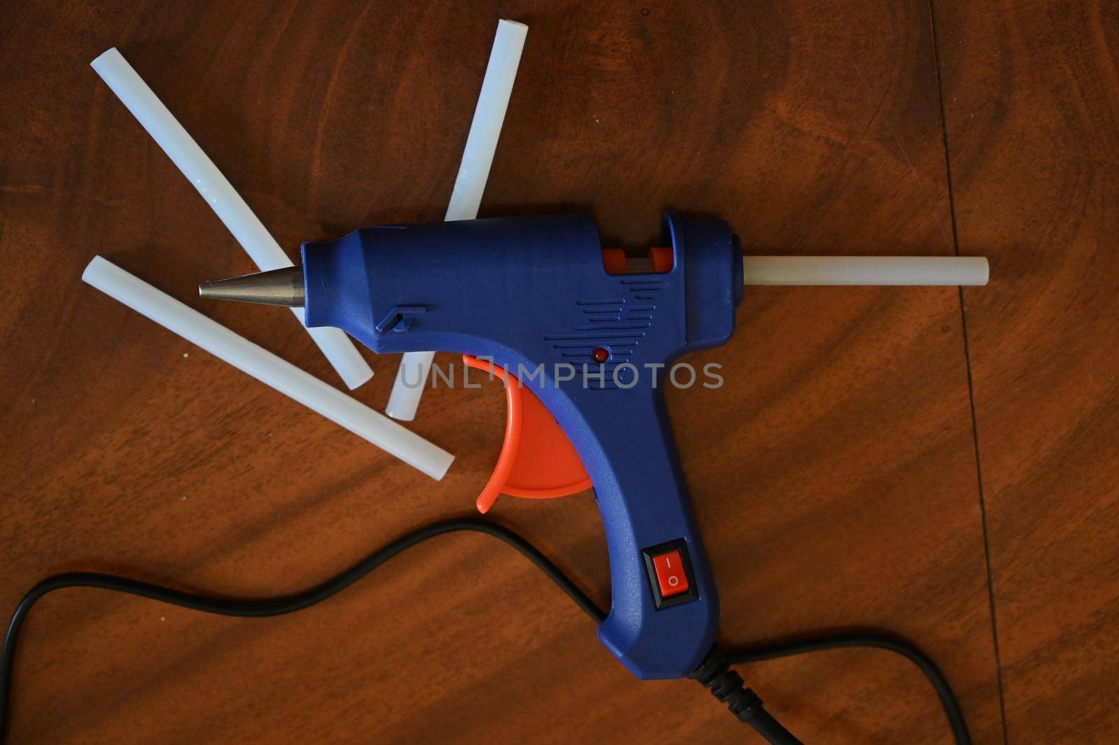 a glue gun with glue rods is lying on the table by ISRAFOTO