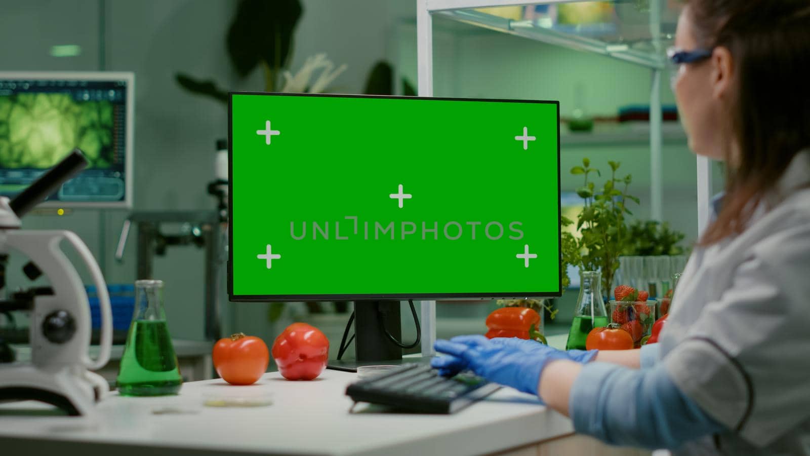 Scientist woman working on computer with mock up green screen by DCStudio