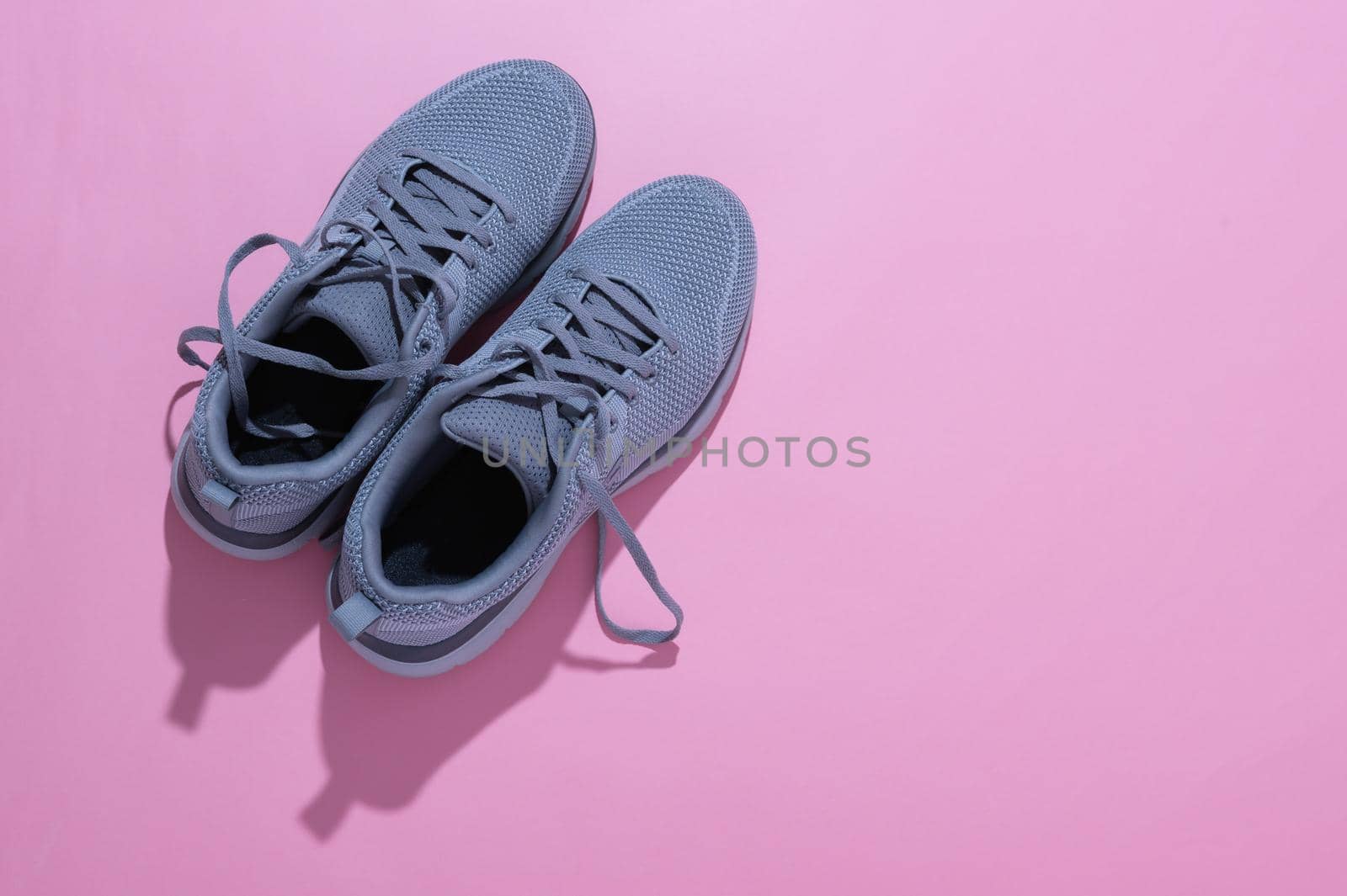 grey sneakers on a pink background by ISRAFOTO